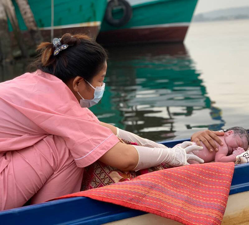 nurse comforting baby and woman in boat on way to hospital in Cambodia