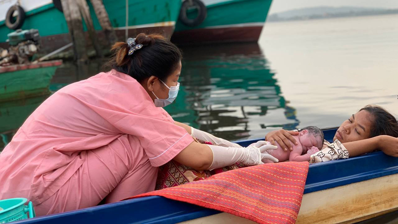 nurse comforting baby and woman in boat on way to hospital in Cambodia