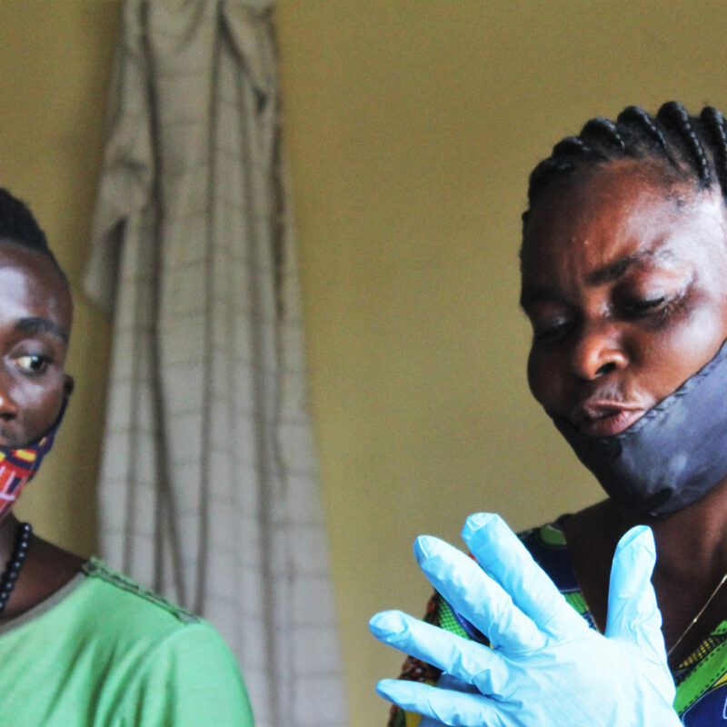 Two people putting on plastic gloves and wearing face masks