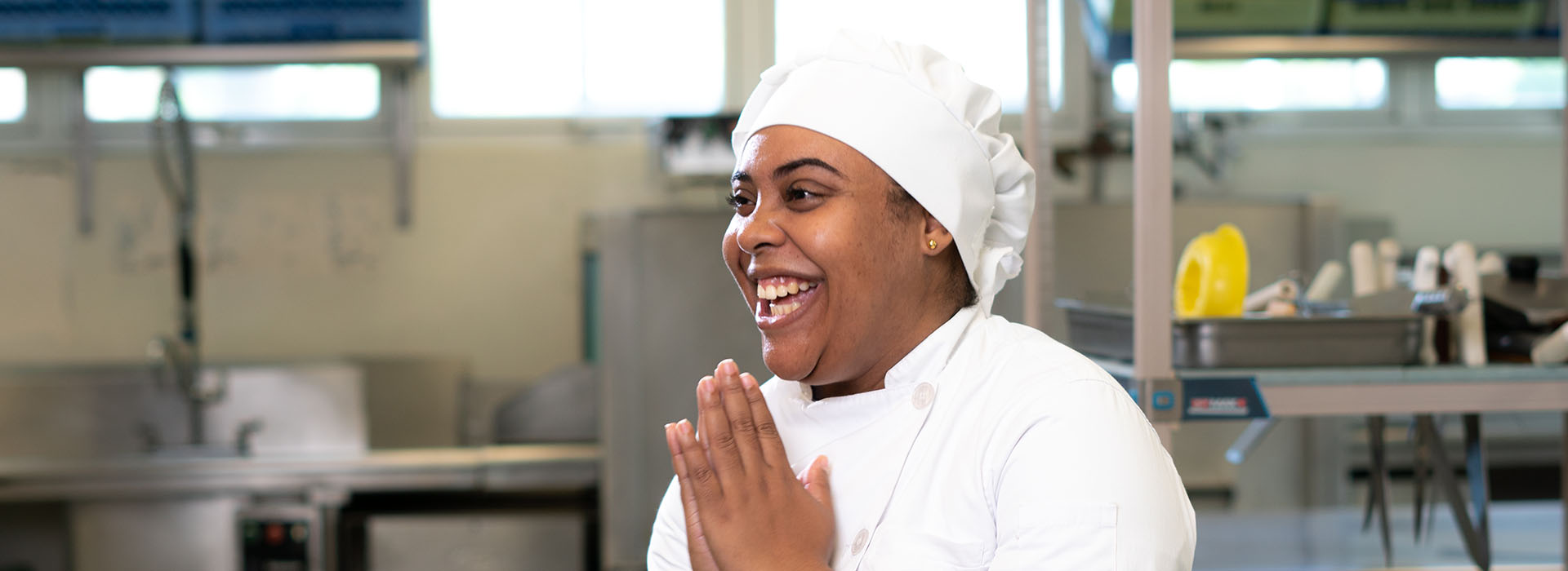 A woman in a chef's uniform laughs