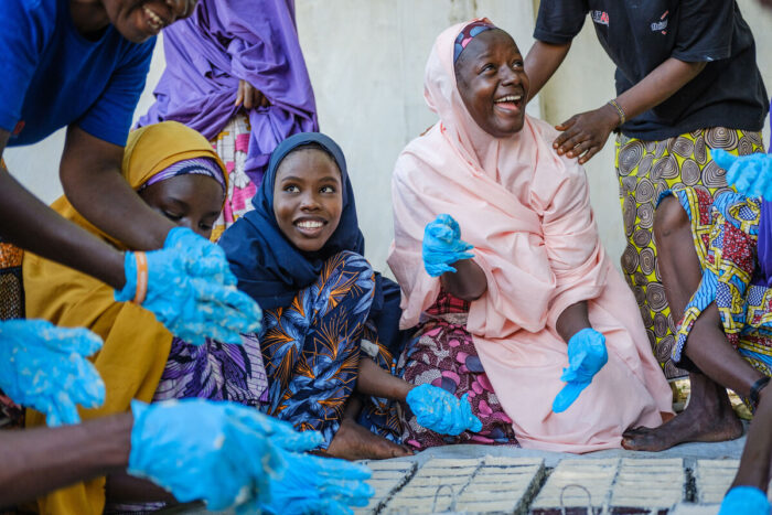 A group of smiling women make soap.