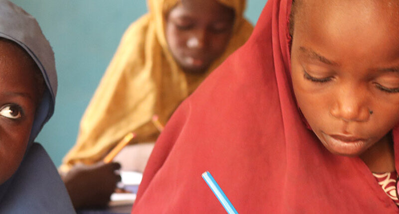 Two young girls listen to their teacher