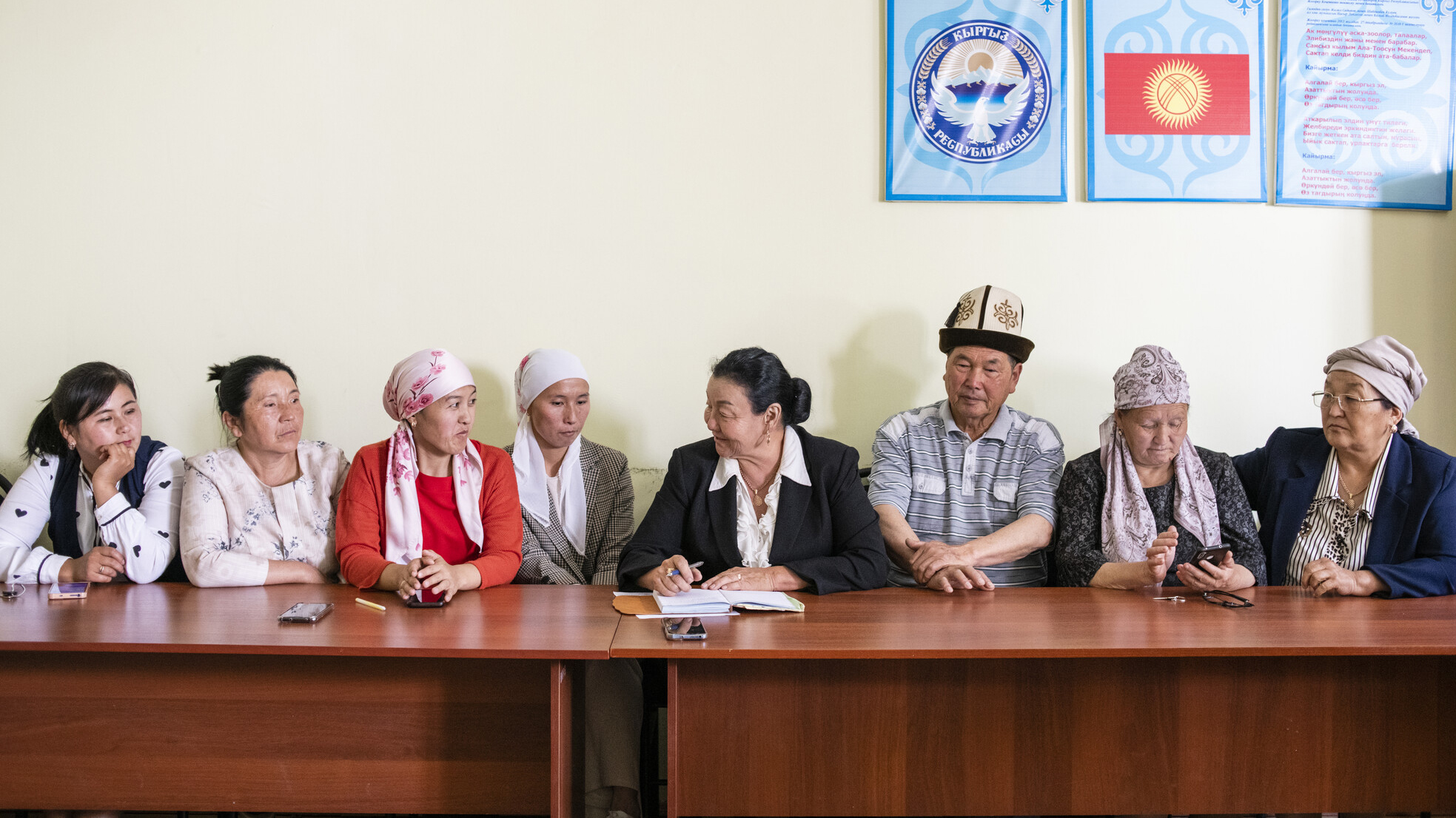 a group of people sitting at a long table looking at a document