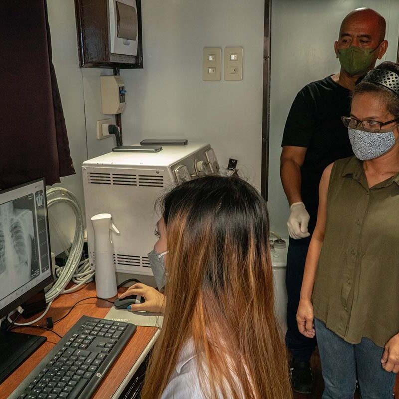 Three people wearing masks review a chest x-ray in an office