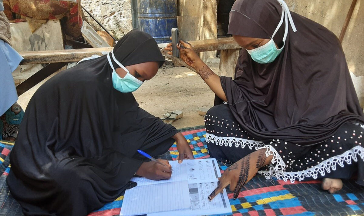 Two girls wearing face masks work on their school work