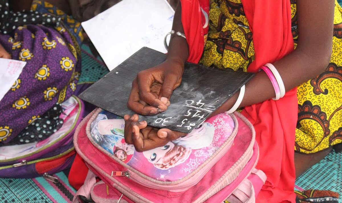 A girl solves a math problem on a handheld chalkboard