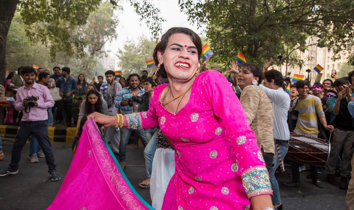 A woman wearing a pink dress dances at a pride parade in New Delhi