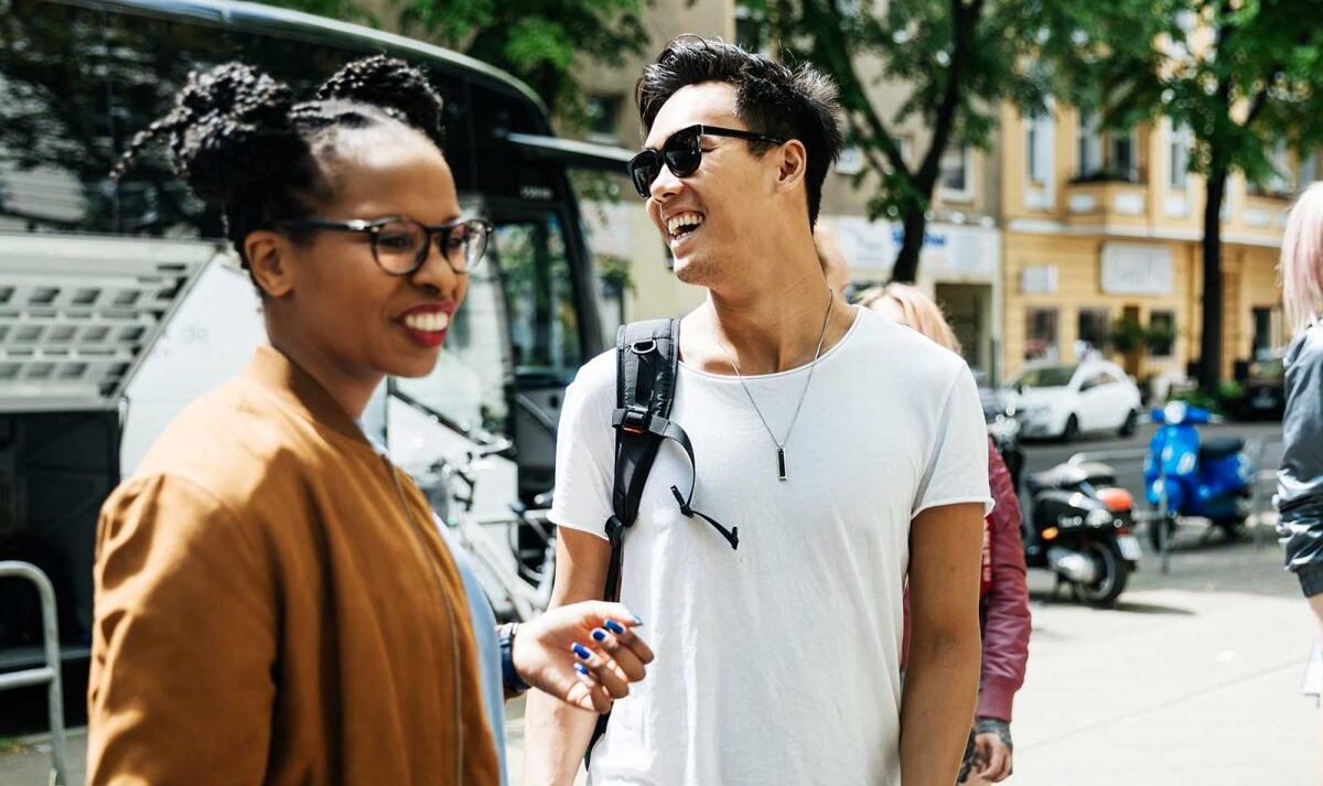 A group of young adults laugh together on a city sidewalk