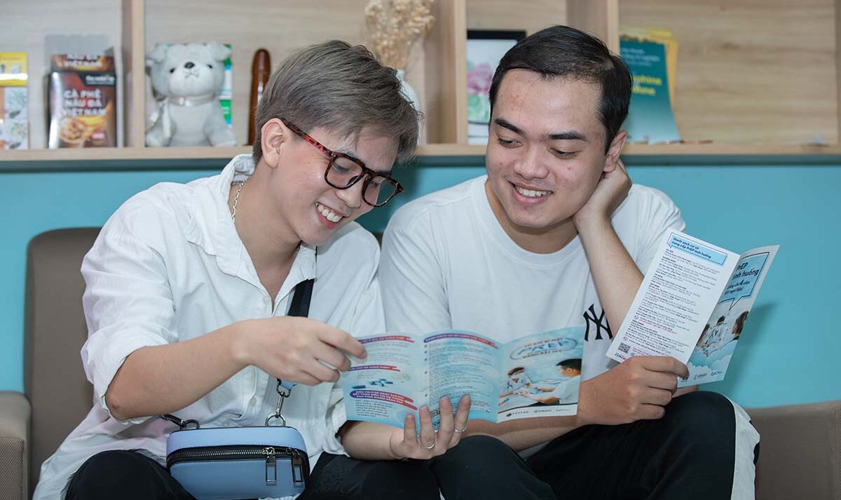 Two young people seated next each other smile while reviewing brochures