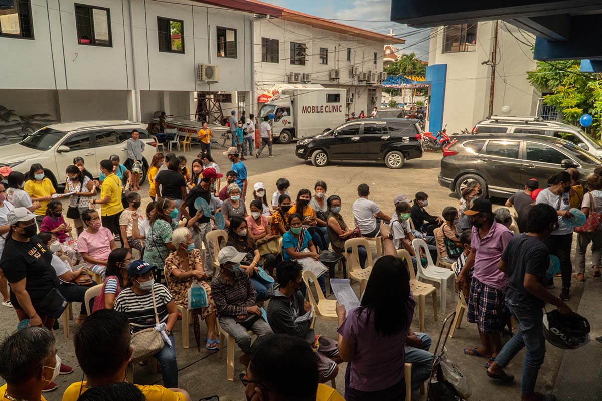 A group of approximately 50 people sits in chairs in an outdoor courtyard in the Philippines.