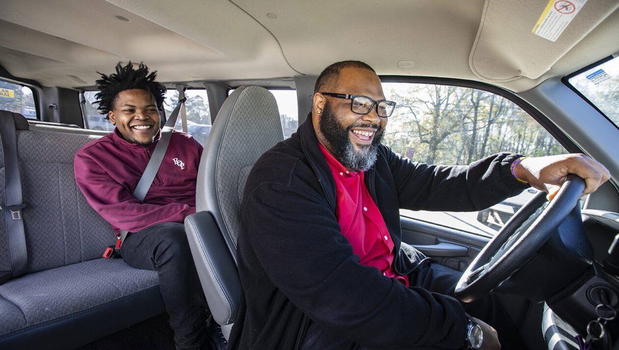 A van driver and teenage passenger laugh together