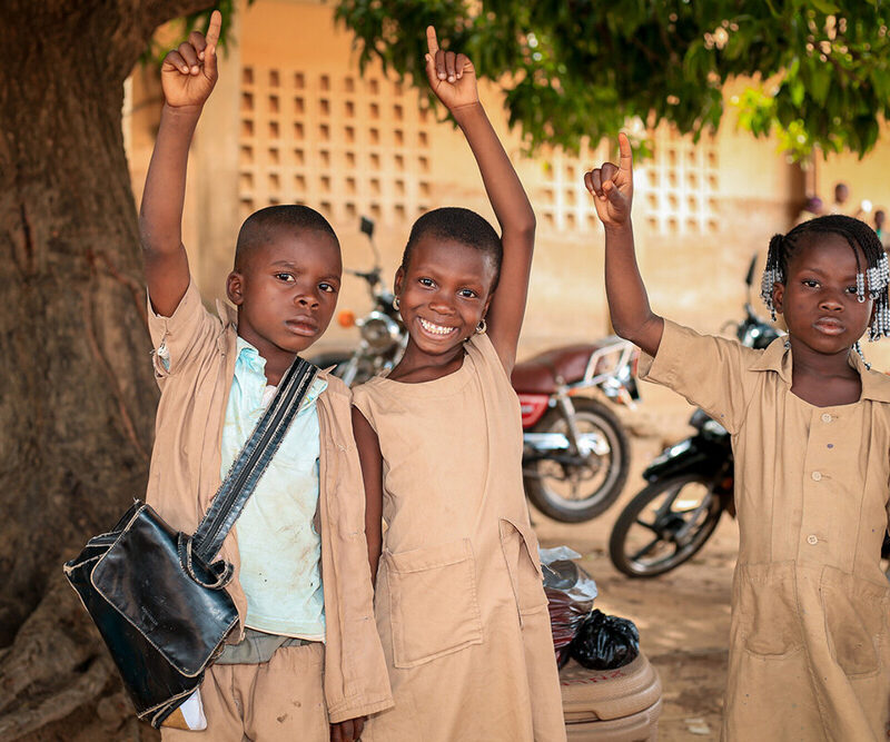 children smiling pointing hands up with pointer finger extended.