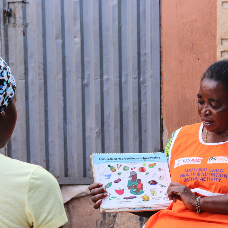 Community health worker sharing nutrition graphic with another woman