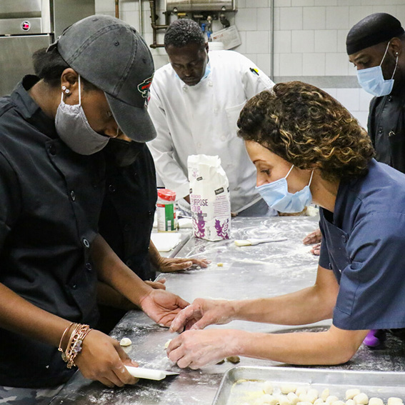 Christa Bruno (right) demonstrates how to knead gnocchi dough during her culinary arts class, which she teaches at the National Center on Institutions and Alternatives in Baltimore, Maryland. Photo credit: Kyle Pompey for FHI 360