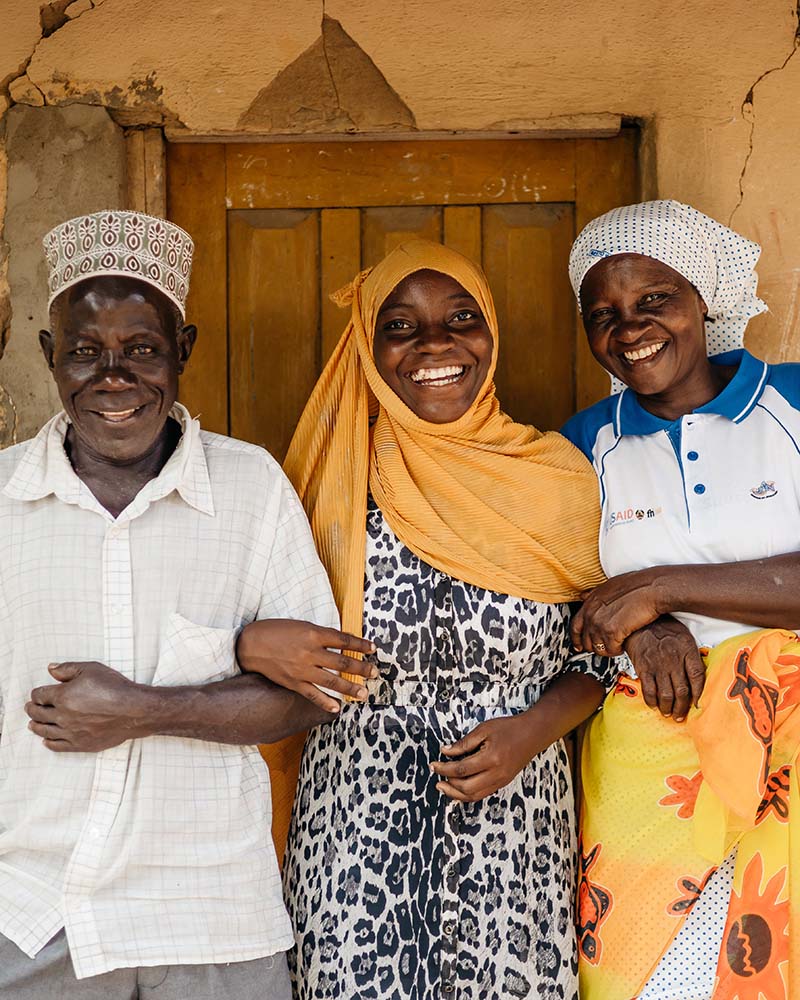 The young woman is linking arms and laughing with her father on the left, and mother on the right.