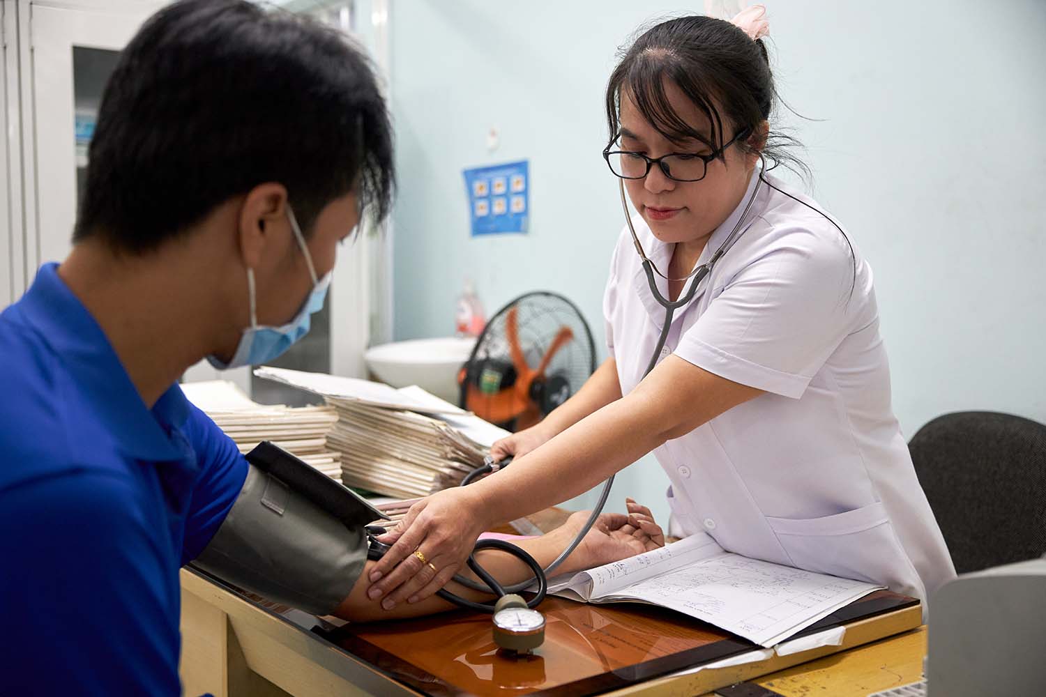 A nurse uses a blood pressure cuff on a patient's arm.