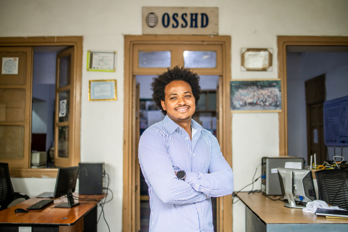 man smiling in office with arms crossed.