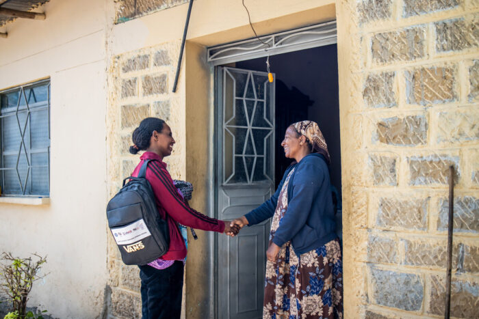 social service worker greets woman during a home visit in Ethiopia.