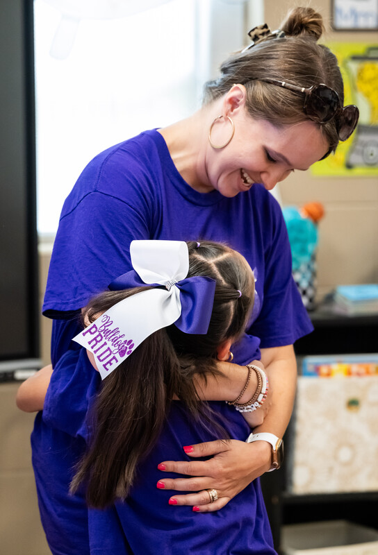 Teacher hugging a young female student