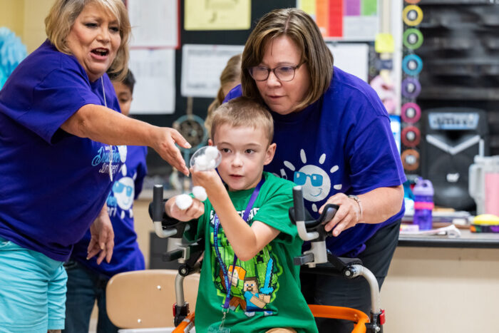 Two teachers help a student with an activity