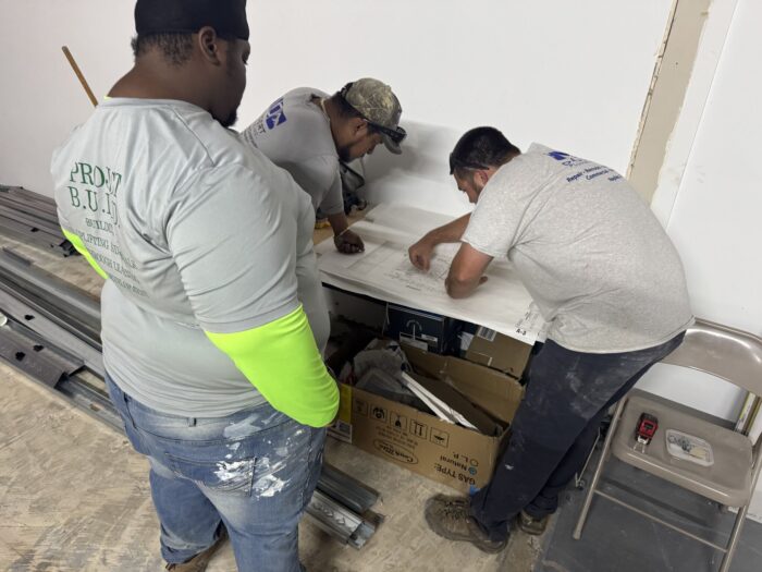 Three men look at building plans