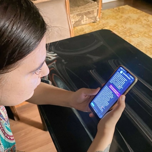 A mother holds her phone and looks at the chatbot on its screen.