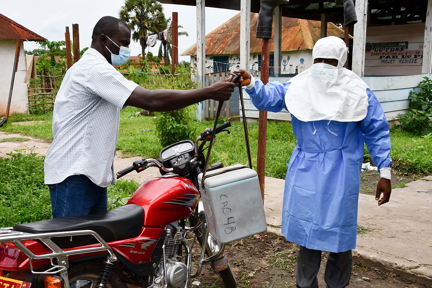 Philippe Bwanga hands off a specimen to Theophile Bobwango, who will take it by motorcycle to be tested for mpox in Equateur Province, Democratic Republic of the Congo.