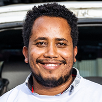 Haben Haleform, a health officer, smiles in front of a truck.