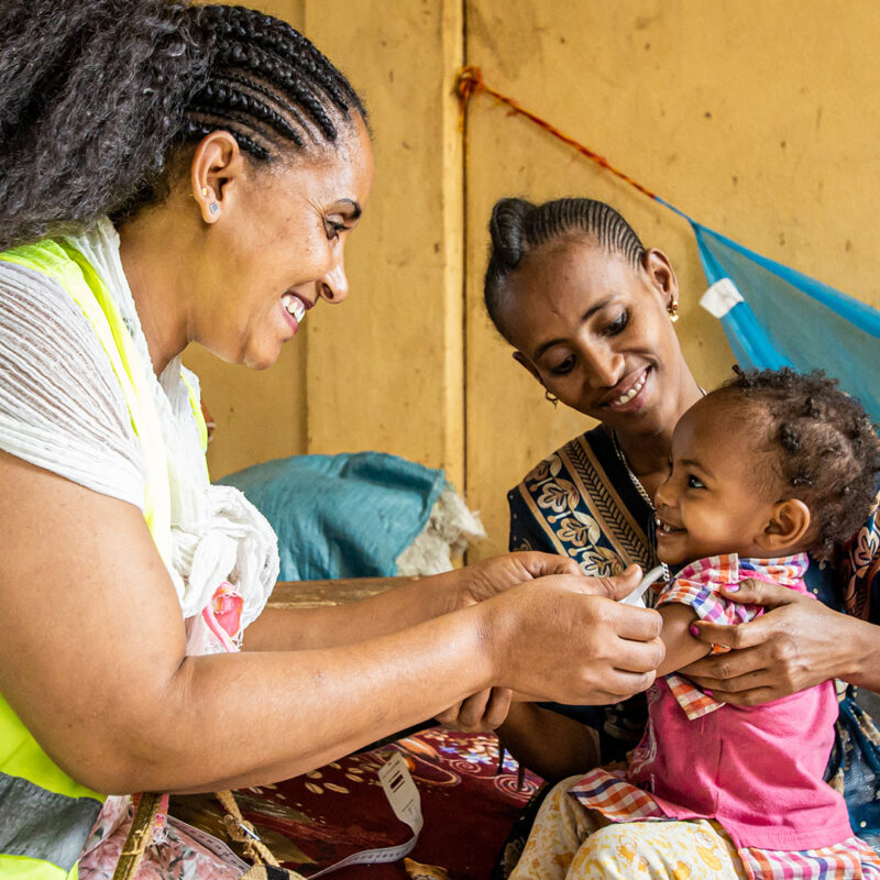 A health worker listens to a boy’s breathing with a stethoscope.