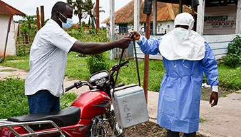 Philippe Bwanga hands off a specimen to Theophile Bobwango, who will take it by motorcycle to be tested for mpox in Equateur Province, Democratic Republic of the Congo.