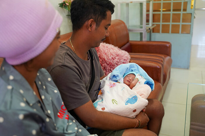 A dad holding his baby wrapped in blankets.