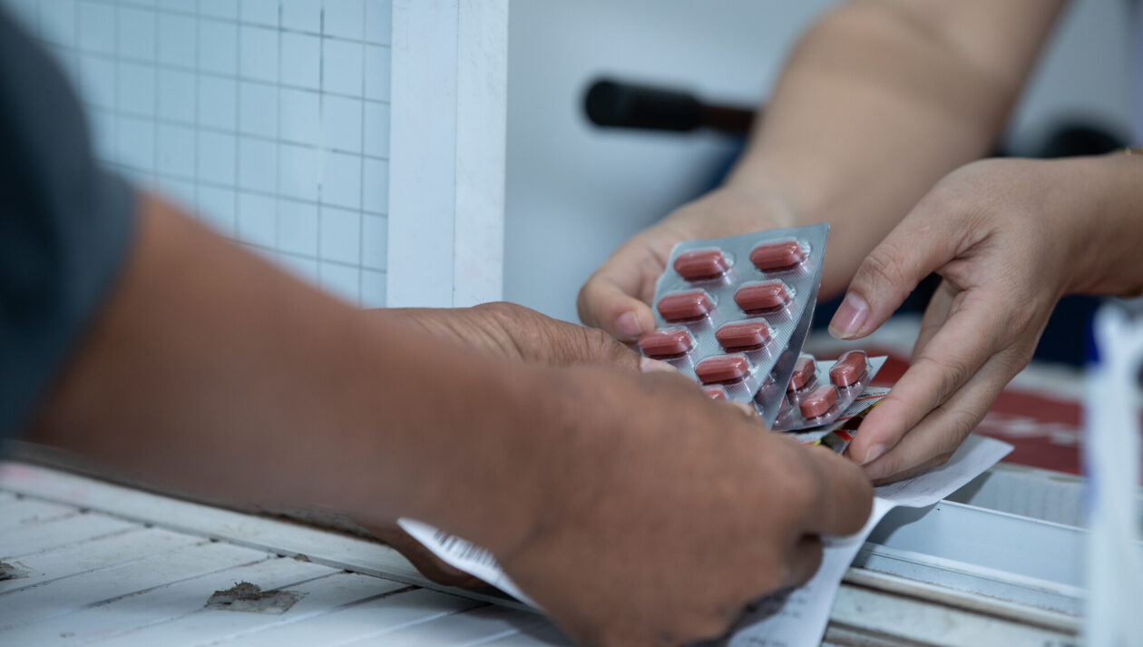 One set of hands passes medication to another set of hands.