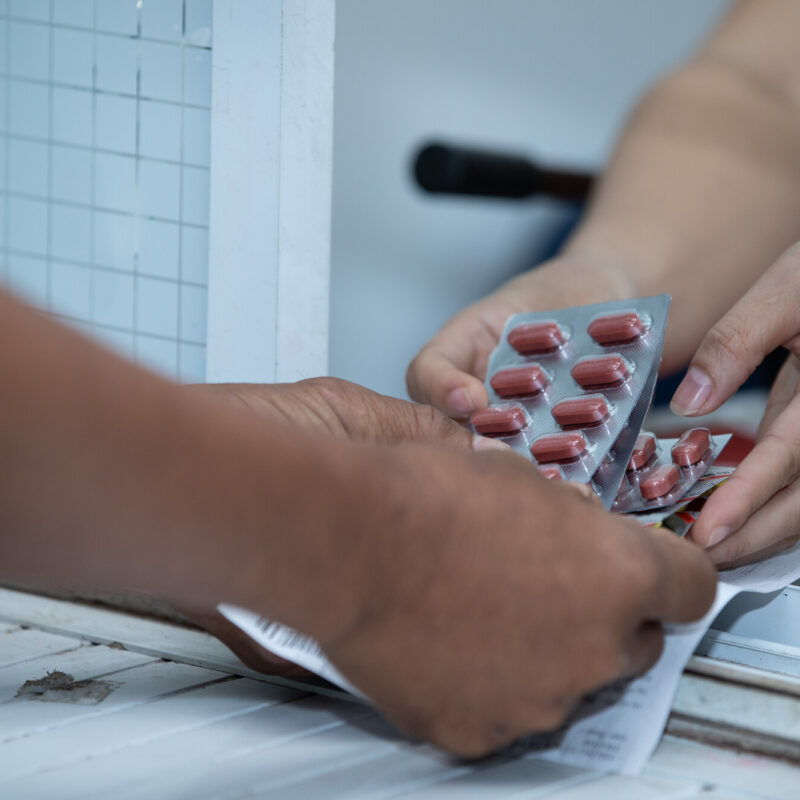 One set of hands passes medication to another set of hands.