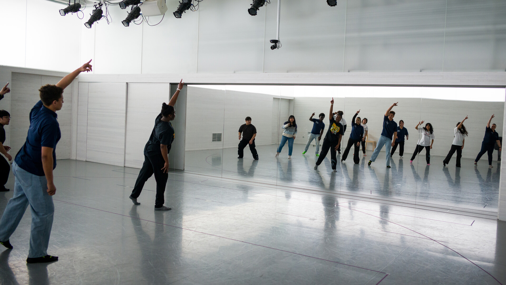 A group of students dancing in front of a large mirror.