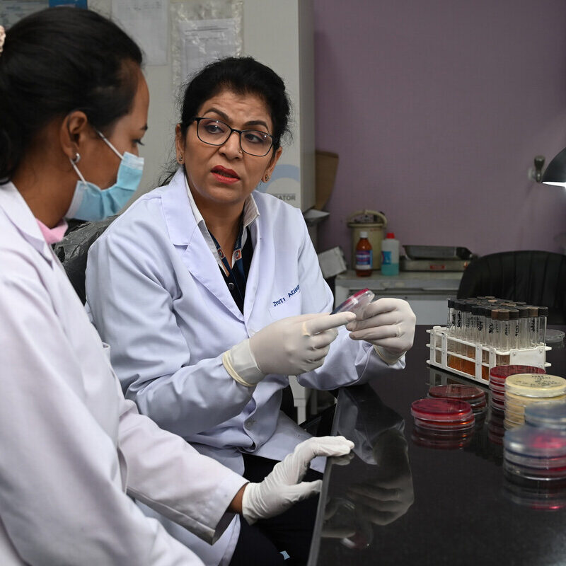 Two women talking while sitting at a desk in a laboratory.