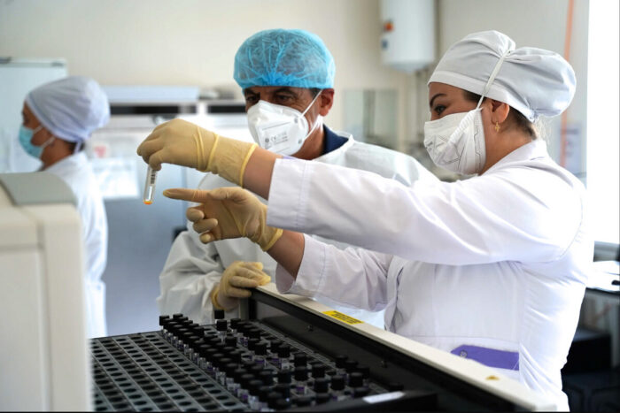 Two lab technicians review a test tube that one is holding.
