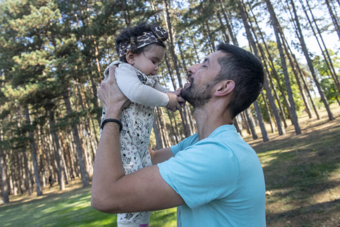 A man playfully holds up a baby
