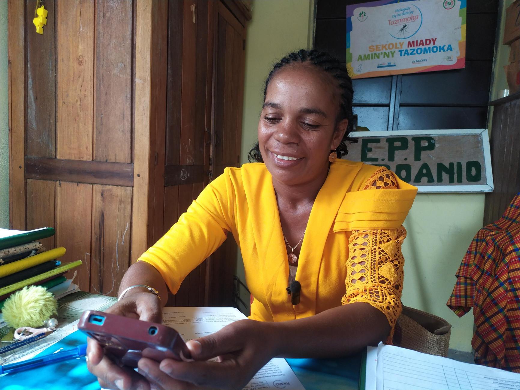 A woman smiles while using a mobile device.