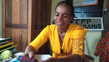 A woman smiles while using a mobile device.