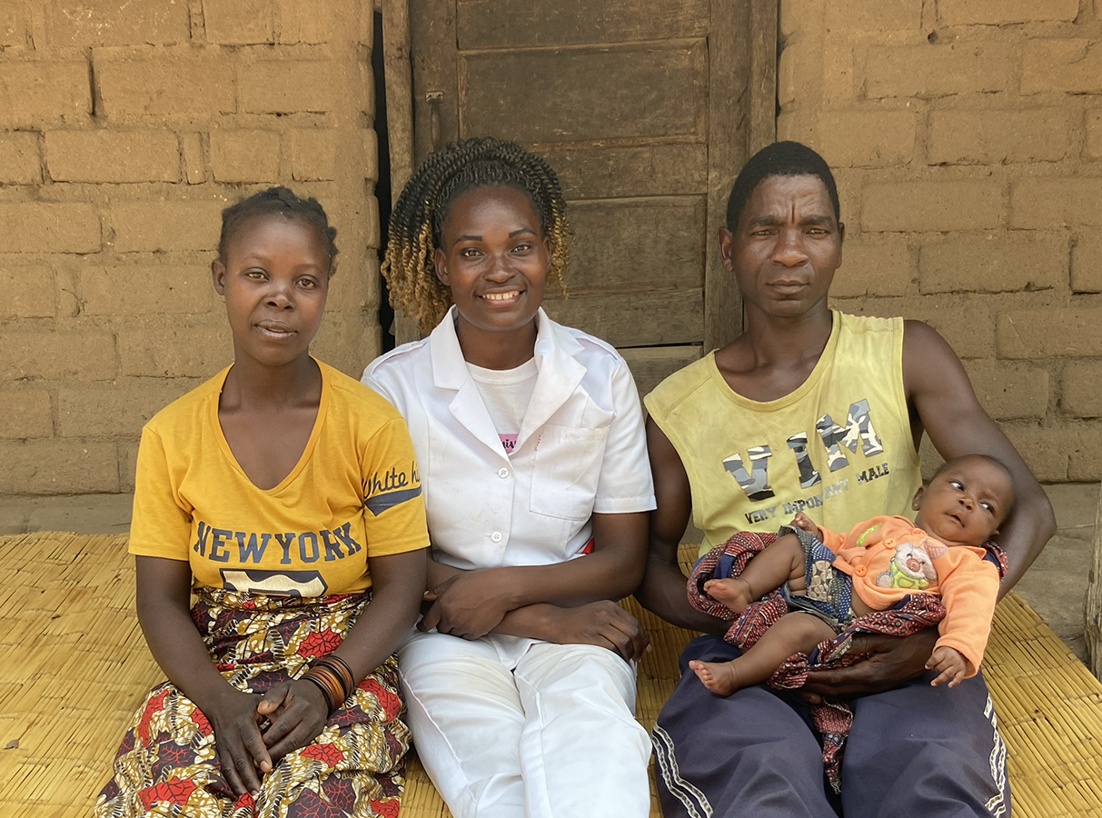 A nurse sits between a woman and a man holding a baby.