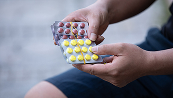 Hands holding two pill packets.