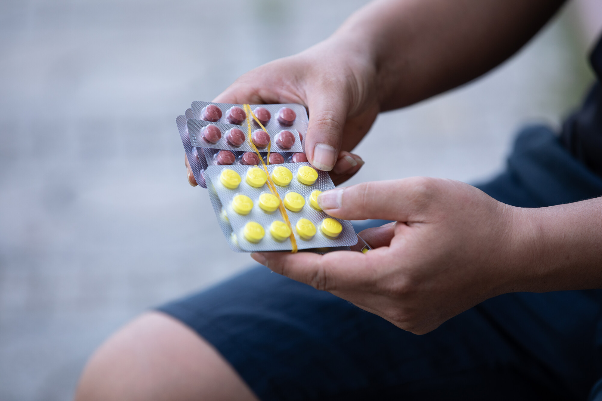 Hands holding two pill packets.