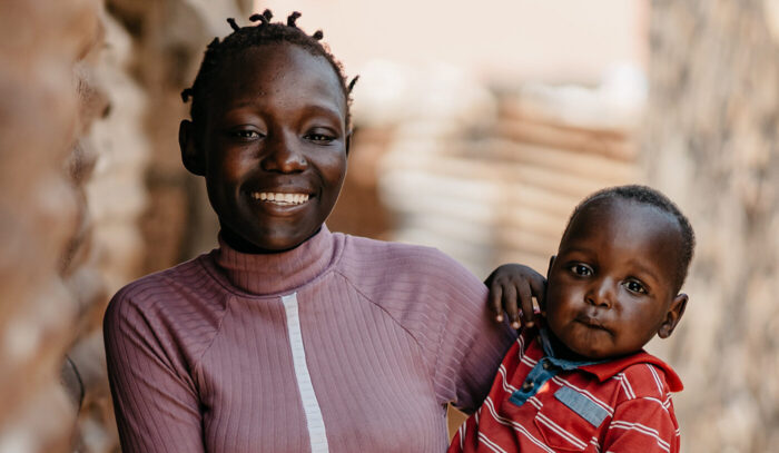 A smiling woman holds a baby on her hip.