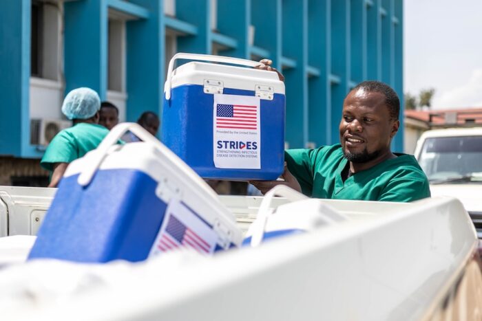 A person holds a cooler next to a truck bed full of coolers.