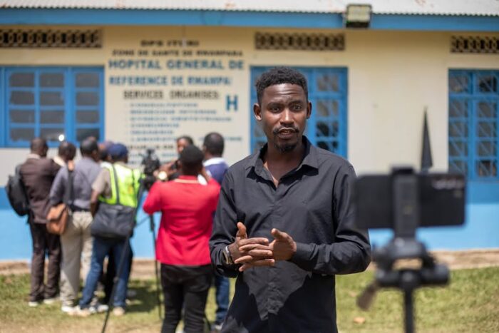 A man stands in front of a crowd outside of a general hospital.