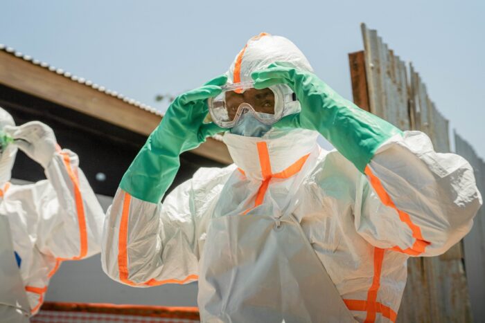 A technician in PPE gear adjusts their goggles.