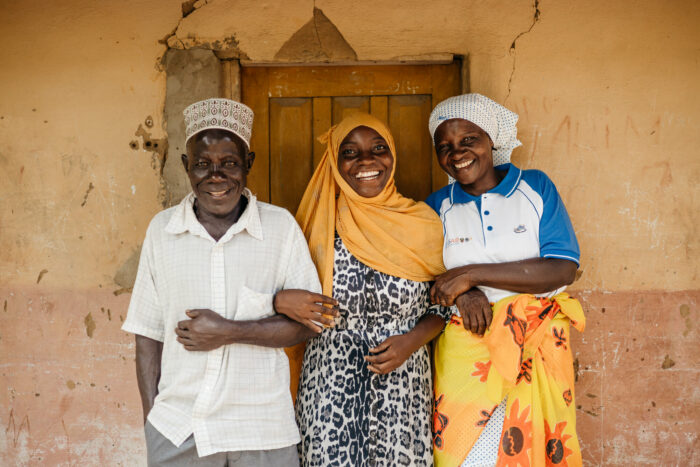 A man and two women, all smiling, standing in front of a door.