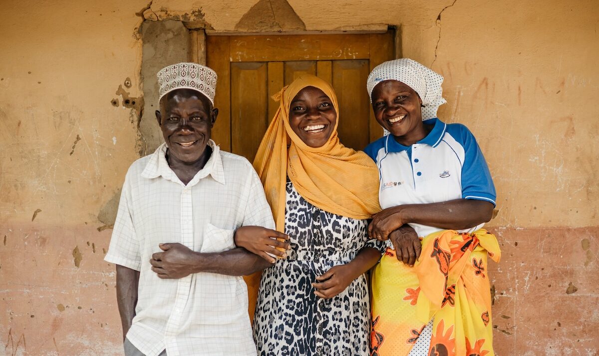 A man and two women, all smiling, standing in front of a door.