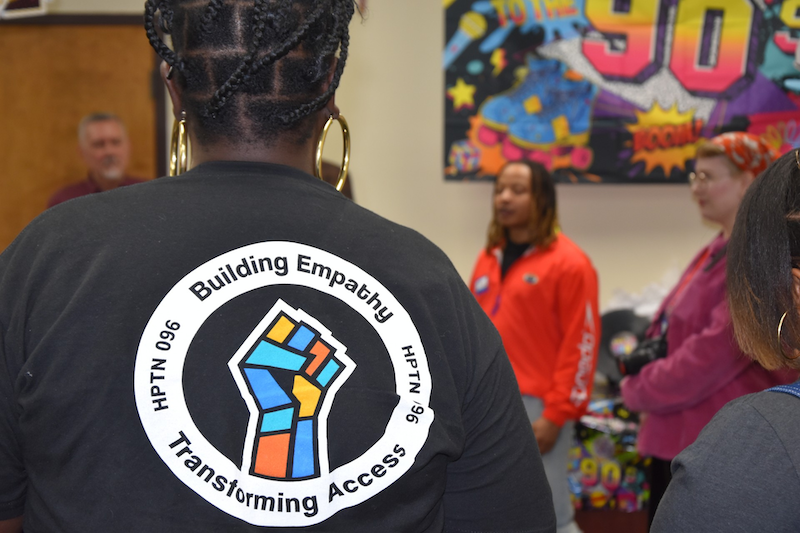 The back of a person wearing a t-shirt that says Building Empathy and Transforming Access
