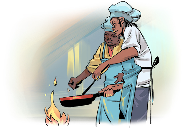 Omar is in a kitchen holding a skillet over an open fire with an instructor chef standing next to him. He is wearing a blue apron over his white shirt and jeans along with a blue chef’s hat. The instructor is wearing a similar blue apron and chef’s hat.